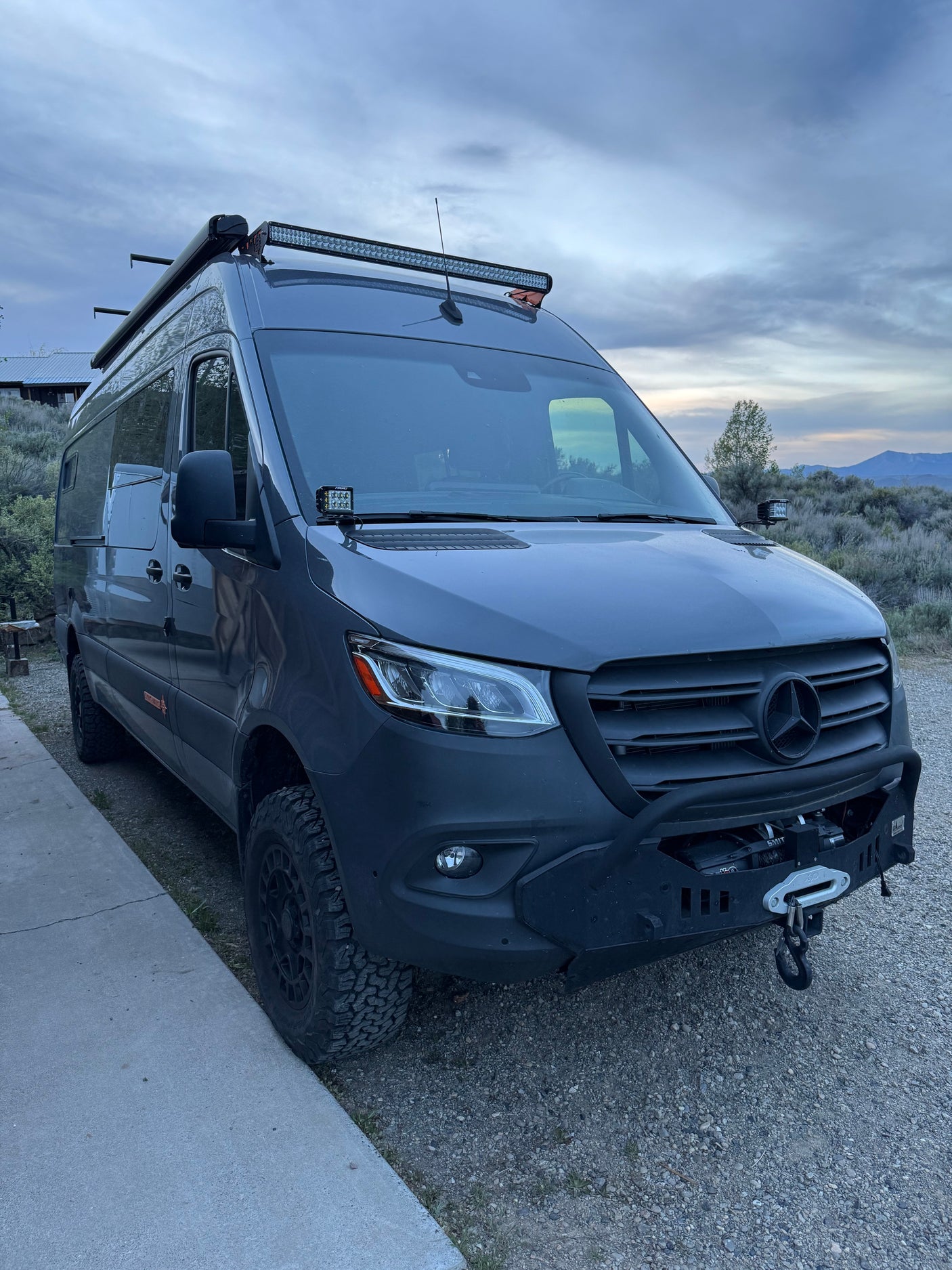 A rugged Mercedes-Benz Sprinter adventure van for rv rental, featuring off-road tires, a front winch, and roof light bar.