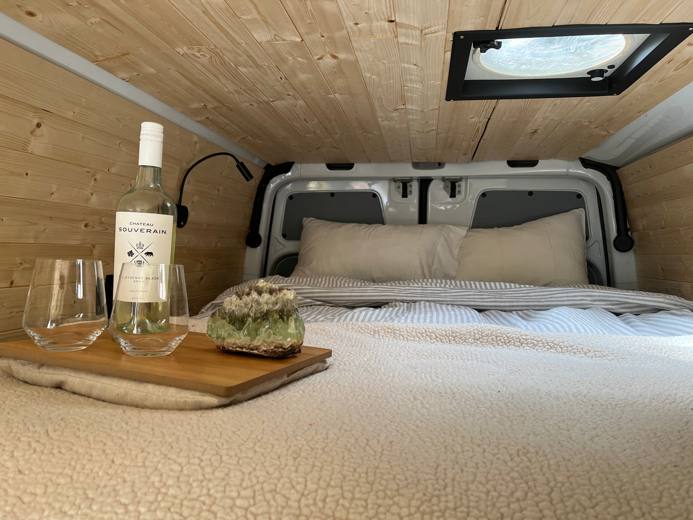 Enjoy a relaxing evening in this cozy RV rental. Features a comfy bed, wood walls, wine, and crystal decor.