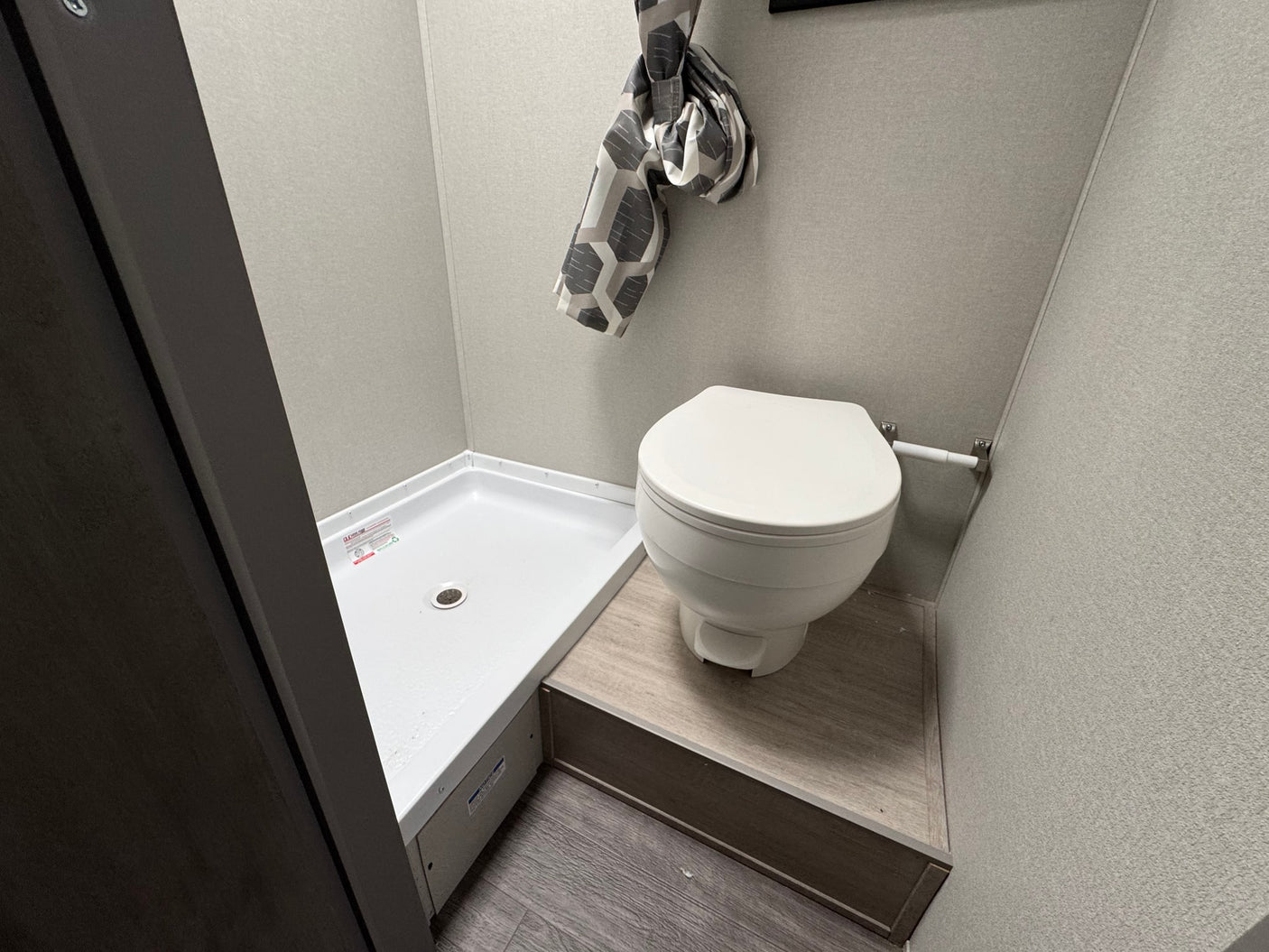 Compact RV rental bathroom: small shower, toilet on platform, modern grey interior. Essential for comfortable travel.