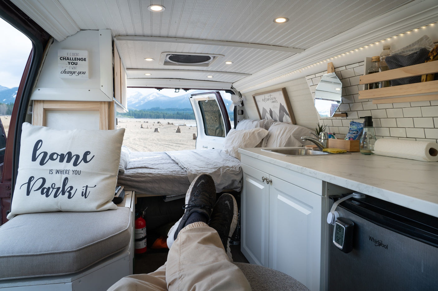 Relaxing in a cozy RV rental van with a scenic mountain view. This custom interior offers comfortable travel adventures.
