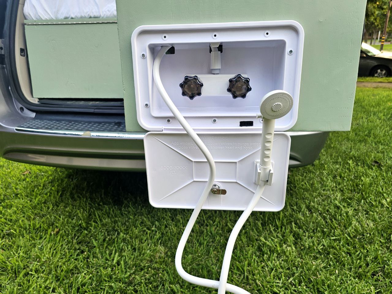 Exterior RV rental shower with hose and hot/cold controls, ideal for outdoor clean-ups on your travels.