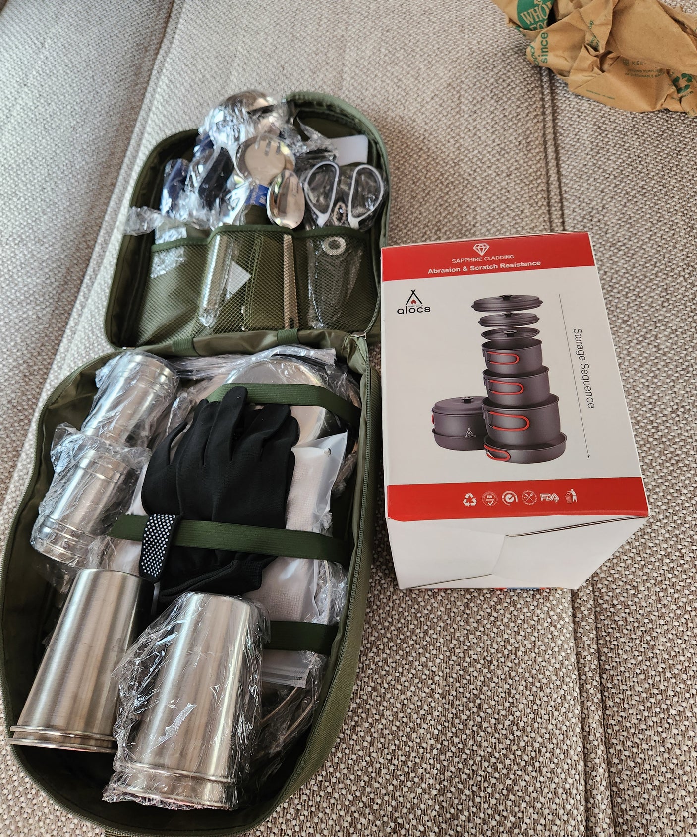 RV rental essentials: Portable camping cookware, utensils, and cups, packed in an olive case, ready for outdoor adventures.