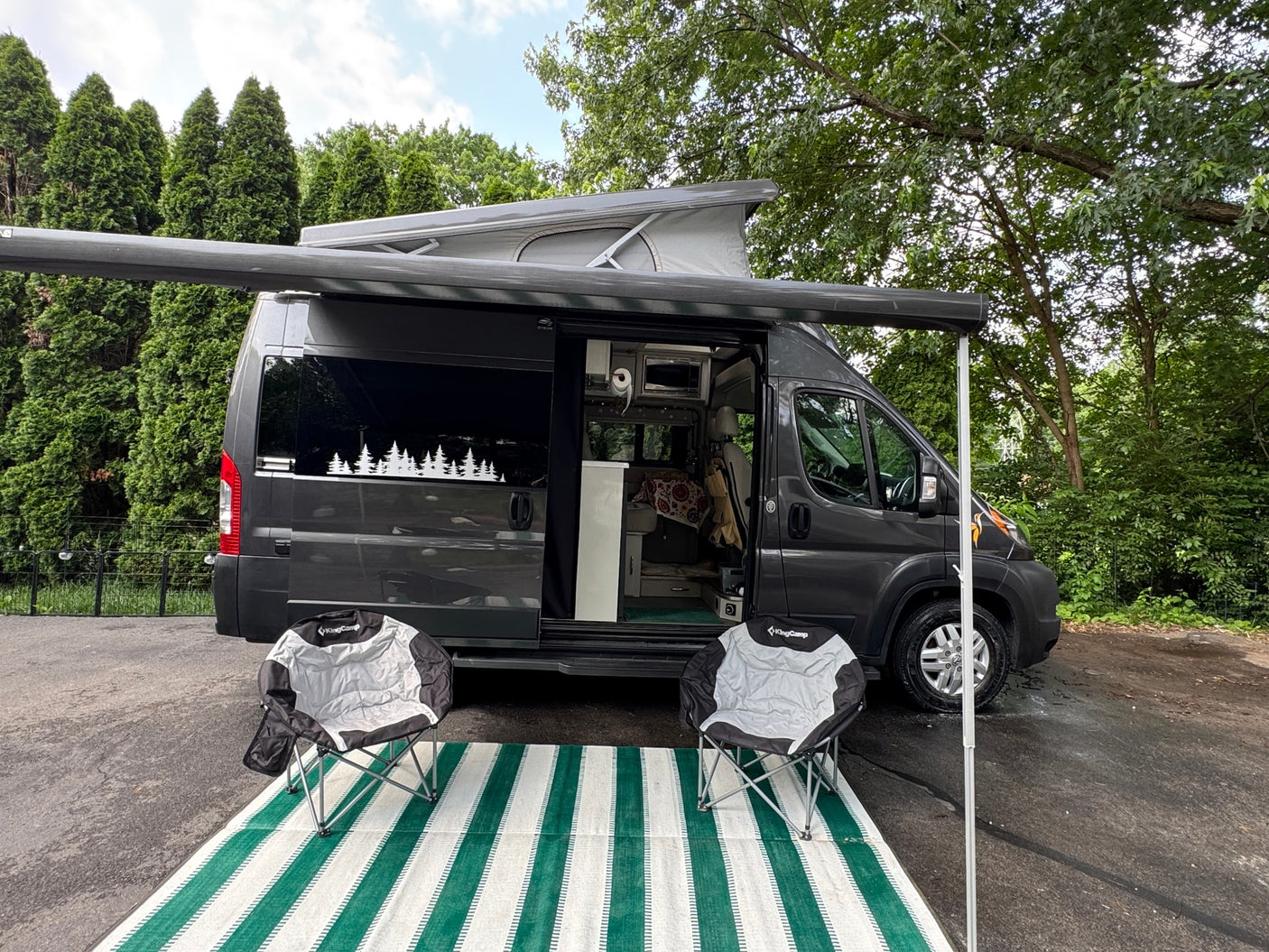 An RV rental camper van with a pop-top, awning, and outdoor living area, ready for your next adventure.