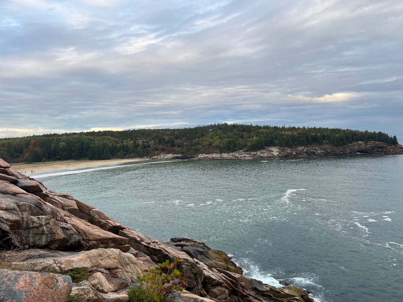 Plan your RV rental trip to this beautiful coastal spot! See rugged rocks, serene water, a sandy beach, and autumn-tinged forests.