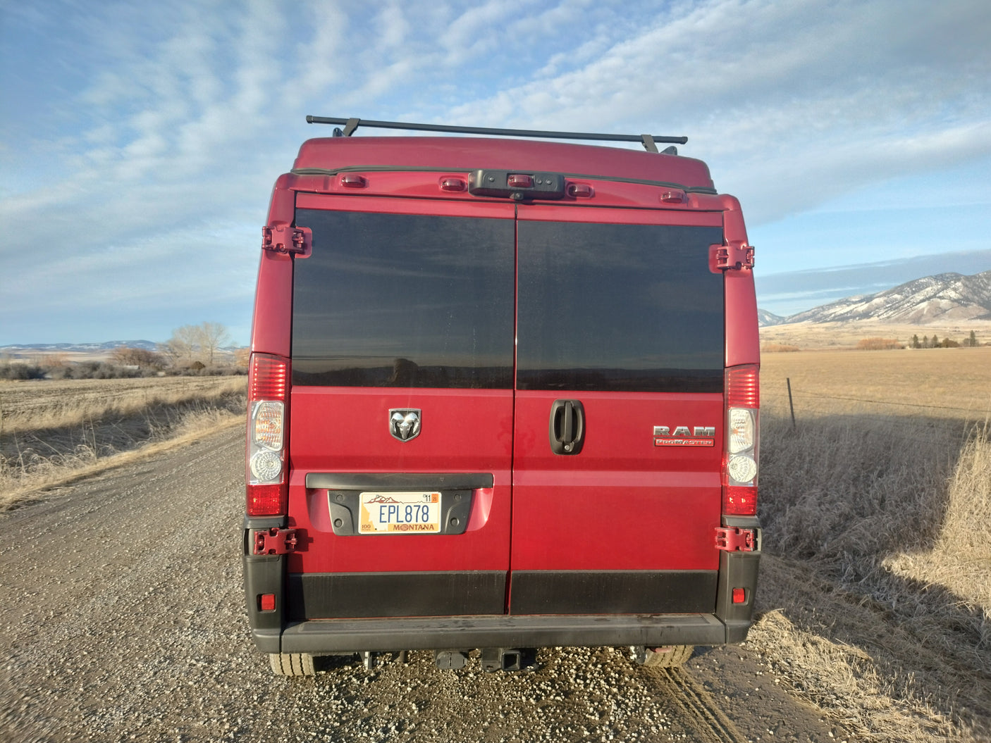 Red Ram ProMaster RV rental on a scenic Montana road, ready for adventure & camping.