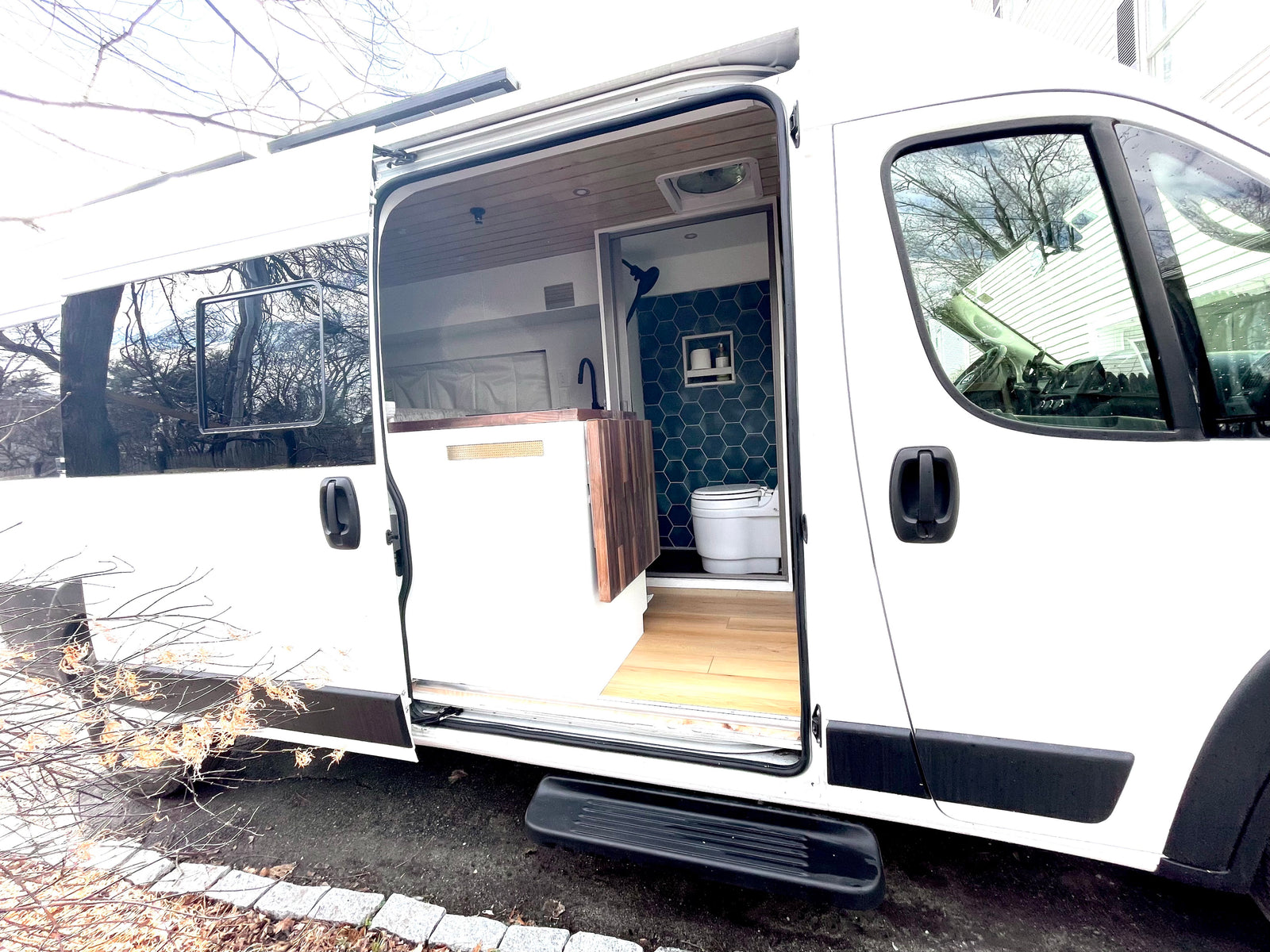 Step inside this modern white RV rental camper van, showcasing its organized kitchen area and stylish tiled bathroom.