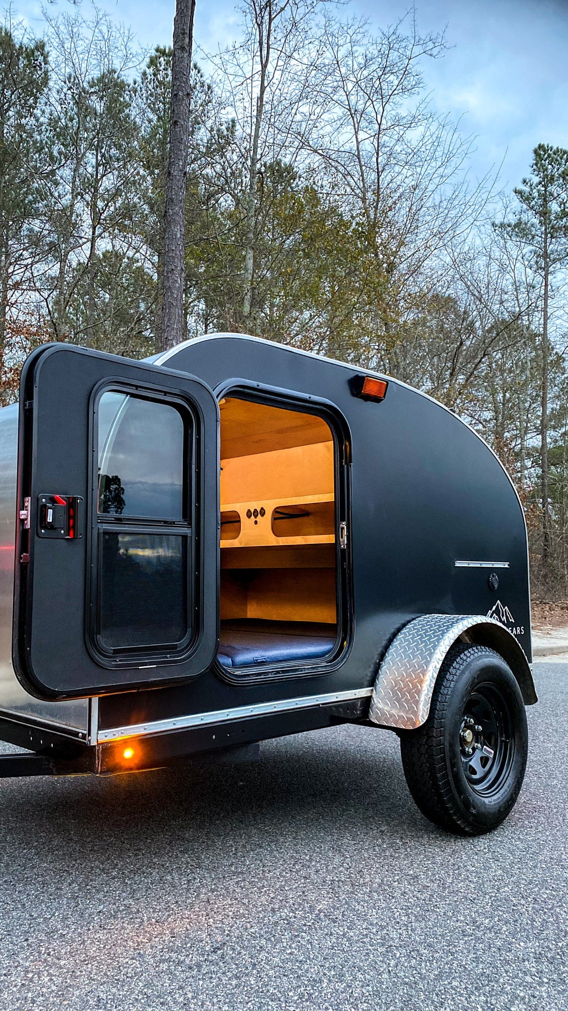 door open revealing wood interior & blue mattress. Perfect for rv rental adventures.|Welcoming RV rental interior: orange bed