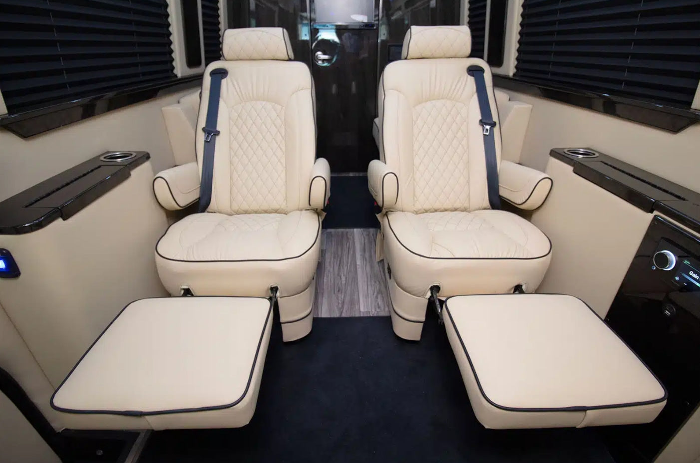 Luxurious RV rental interior features cream captain's chairs, footrests, and side consoles for comfort.
