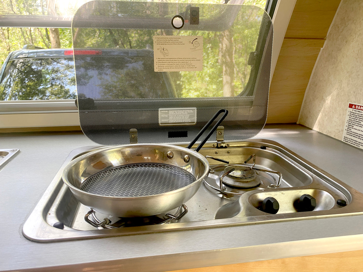 RV rental kitchen: a compact stove and pan, with cooking instructions on the open glass lid, ready for campsite meals.