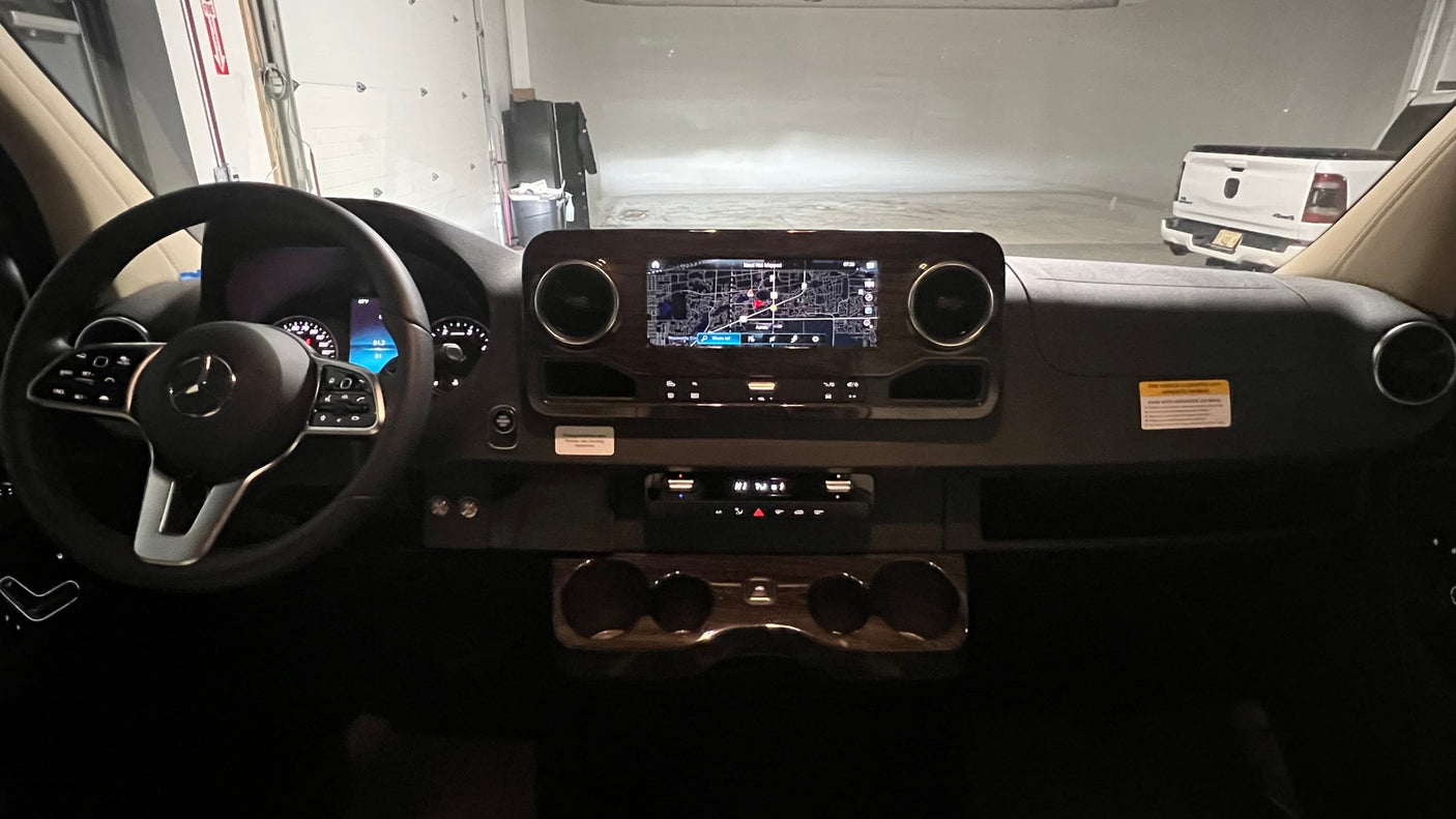 RV rental dashboard showing Mercedes-Benz steering wheel, navigation system with map, climate controls, and cup holders.