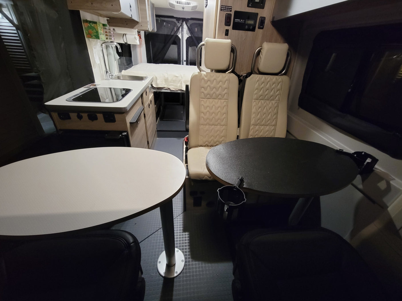 Explore this comfy RV rental interior: kitchen, dining tables, and a rear bed for convenient mobile living.