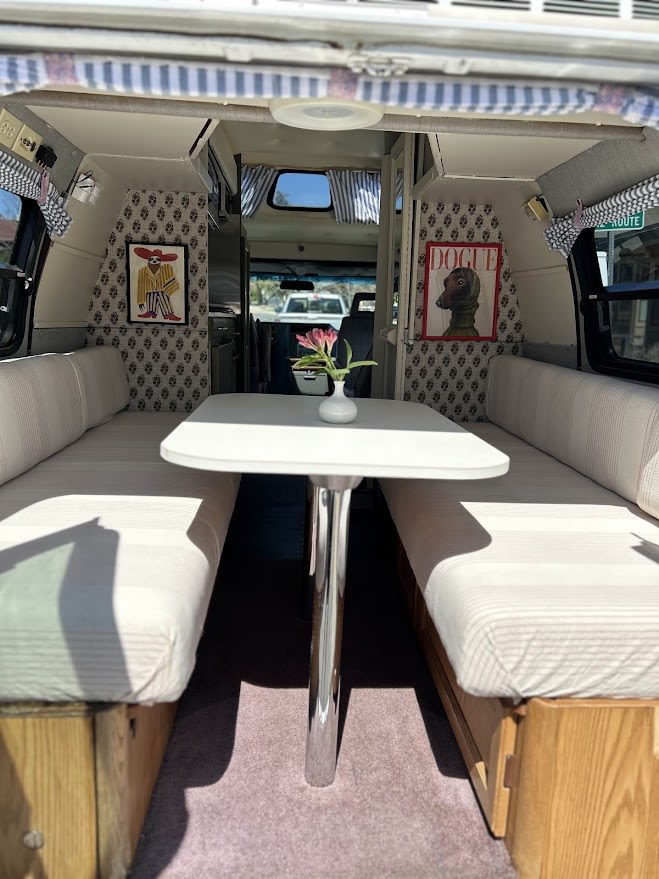 Stylish rv rental interior: dining booth with striped cushions, patterned walls, and fun artwork. Ready for your journey.