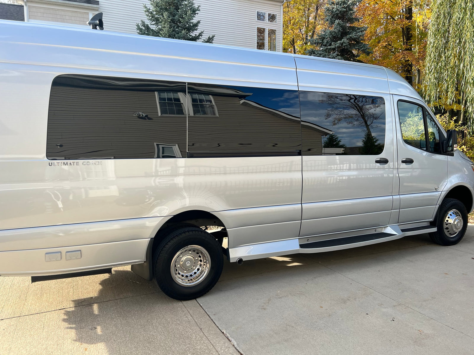 Modern silver Mercedes Sprinter RV, an 'ULTIMATE COACH', perfect for rv rental. View of side exterior.