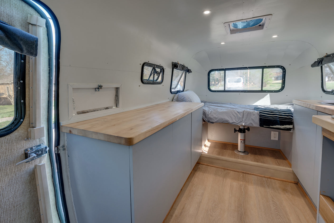 Spacious rv rental interior featuring a cozy bed, ample wood countertops, and practical storage solutions.