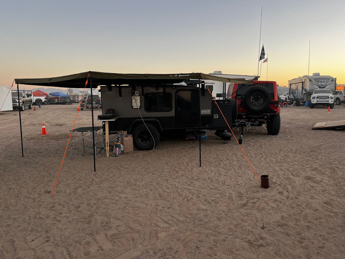 is parked at a Chevron gas station.|Red Jeep & rugged overland trailer parked in a sunny desert landscape with mountains. Explore with an off-road RV rental!|Icy Hiker Trailer RV rental