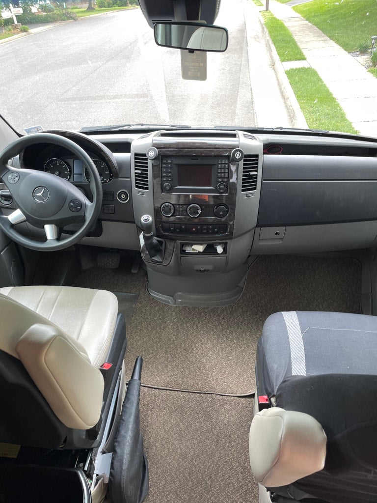 parked on a residential street under a cloudy sky.|RV rental: Interior living area with a large gray sofa