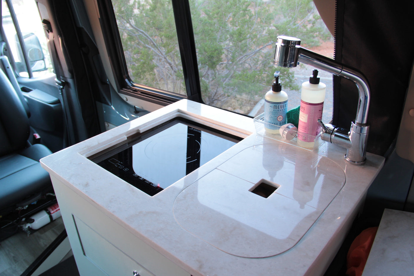 Compact RV rental kitchen featuring a modern induction cooktop, sink, and faucet, perfect for on-the-go cooking.