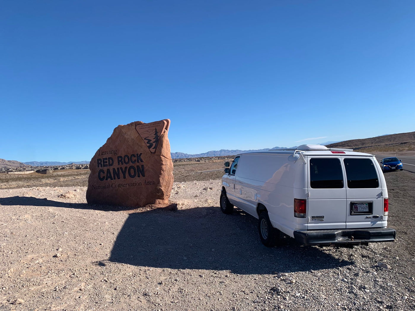 with desert mountains and blue sky.|An RV rental van exits Red Rock Canyon National Conservation Area — photo 2