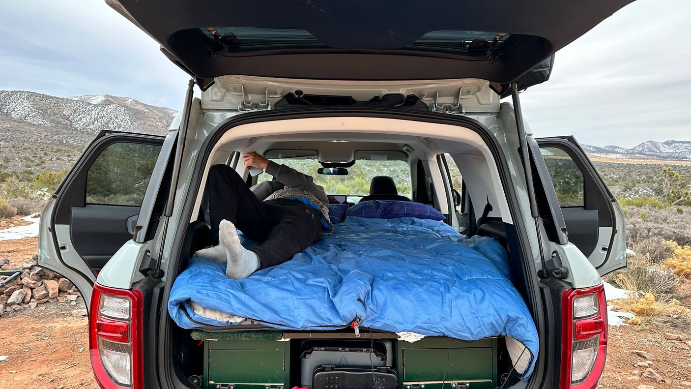 a snowy desert and mountains at sunset. Consider an RV rental!|This SUV's cozy car camping setup
