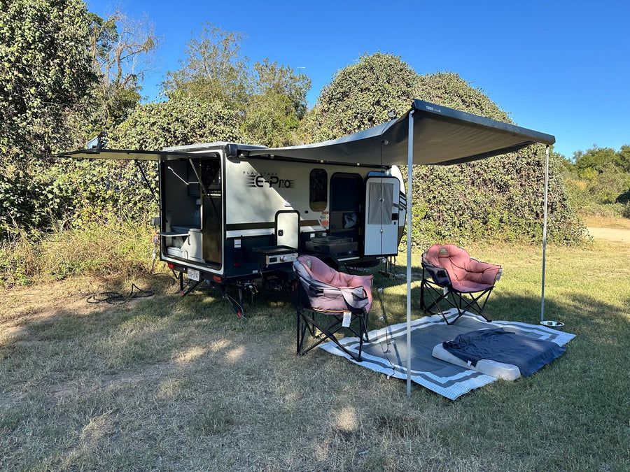 This Flagstaff E-Pro RV rental is perfectly set up for camping, featuring an extended awning, chairs, and outdoor kitchen.