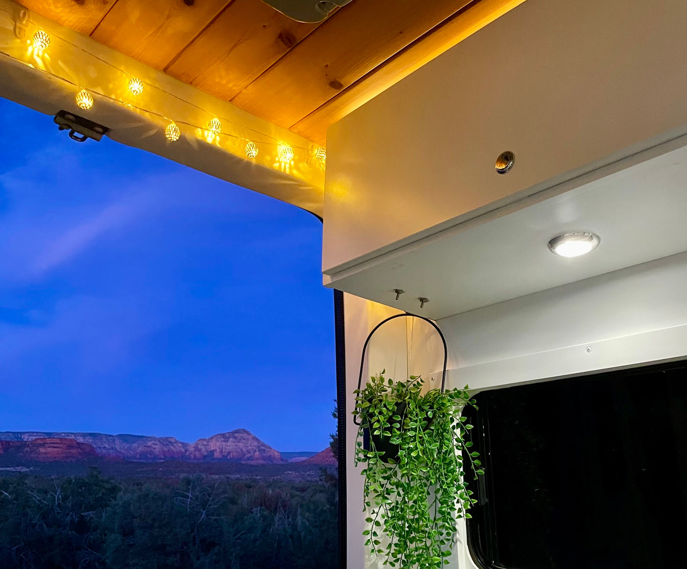 Cozy RV rental interior with warm lights & stunning red rock mountain view at twilight. Perfect for adventure!