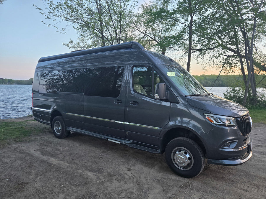 Dark grey Mercedes Sprinter camper van (RV rental) by a serene lake. Perfect for outdoor adventures and nature travel.