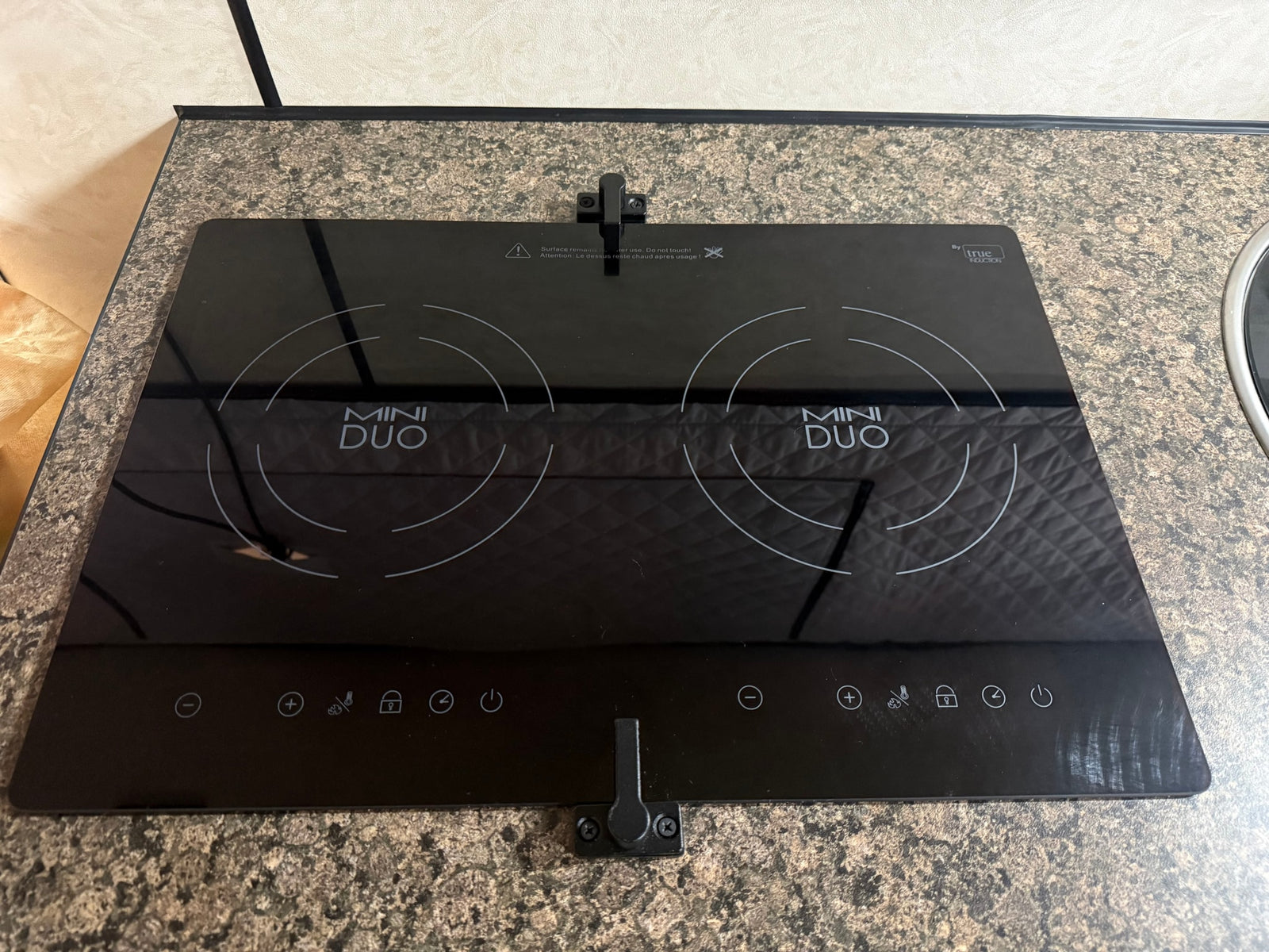 This rv rental kitchen features a modern black "MINI DUO" two-burner induction cooktop with digital touch controls.