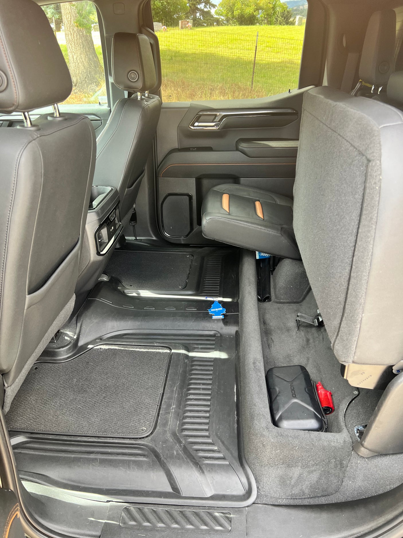 Spacious rear cabin of a truck or SUV, great for an RV rental or road trip. Shows protective floor mats & folded seat for cargo.