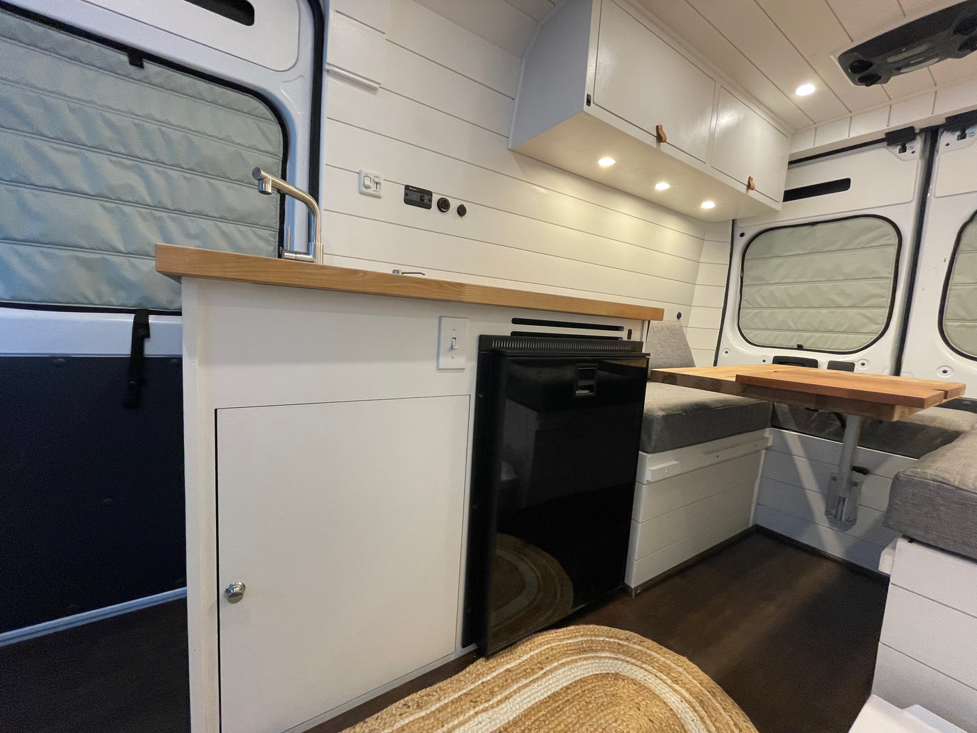 Bright, modern RV rental interior: a compact kitchen with a sink & fridge, and a cozy dinette space.