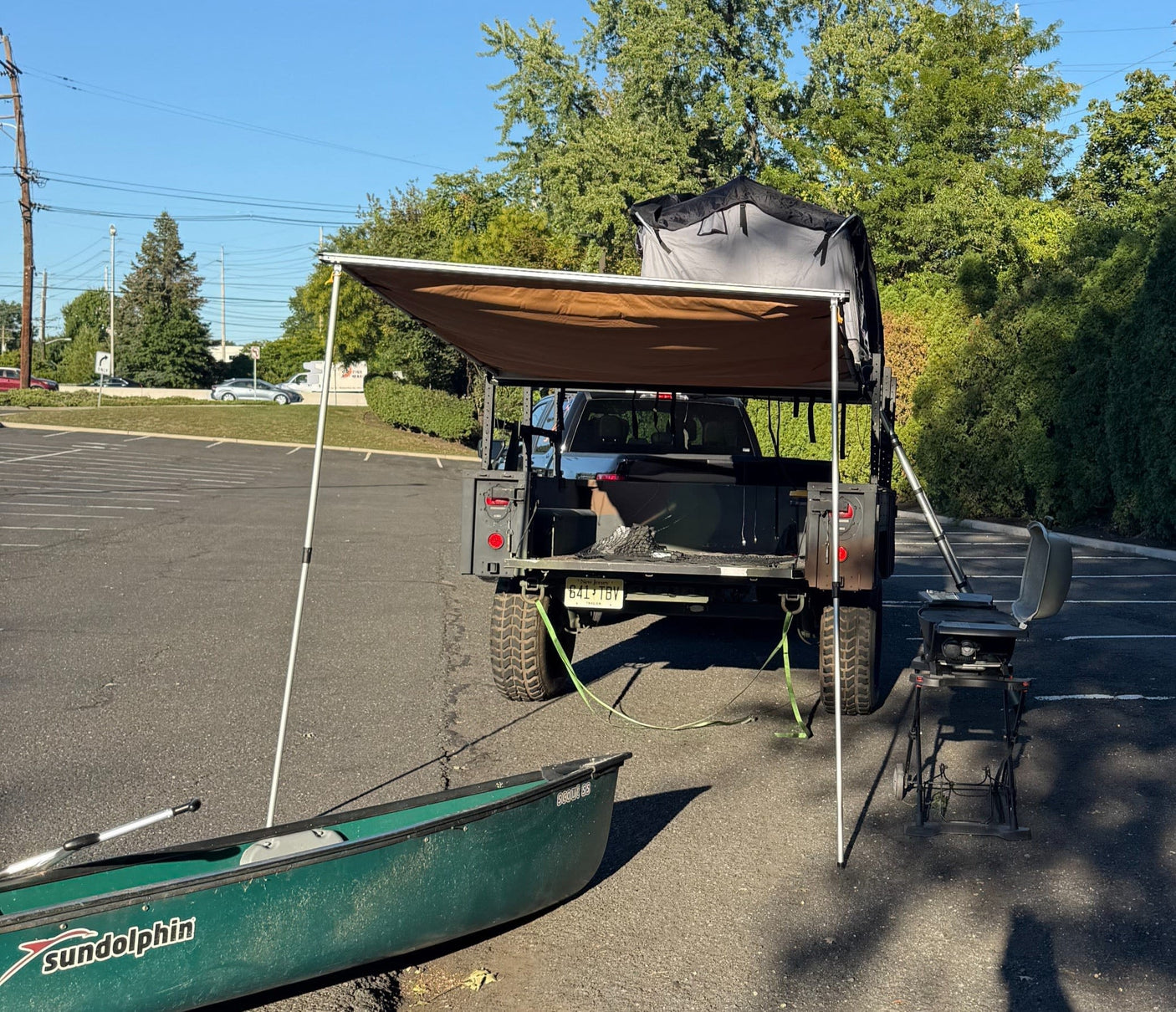 and SUV under trees.|Enjoying an RV rental adventure: a warm campfire glows next to a vehicle with a rooftop tent and ladder under the night sky.|A pickup truck tows a camouflage utility trailer with a canoe and rooftop tent