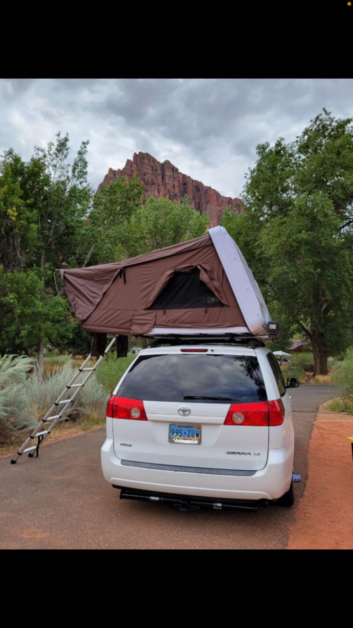 ideal for an RV rental camping trip.|White minivan with a brown rooftop tent deployed in a scenic — photo 4