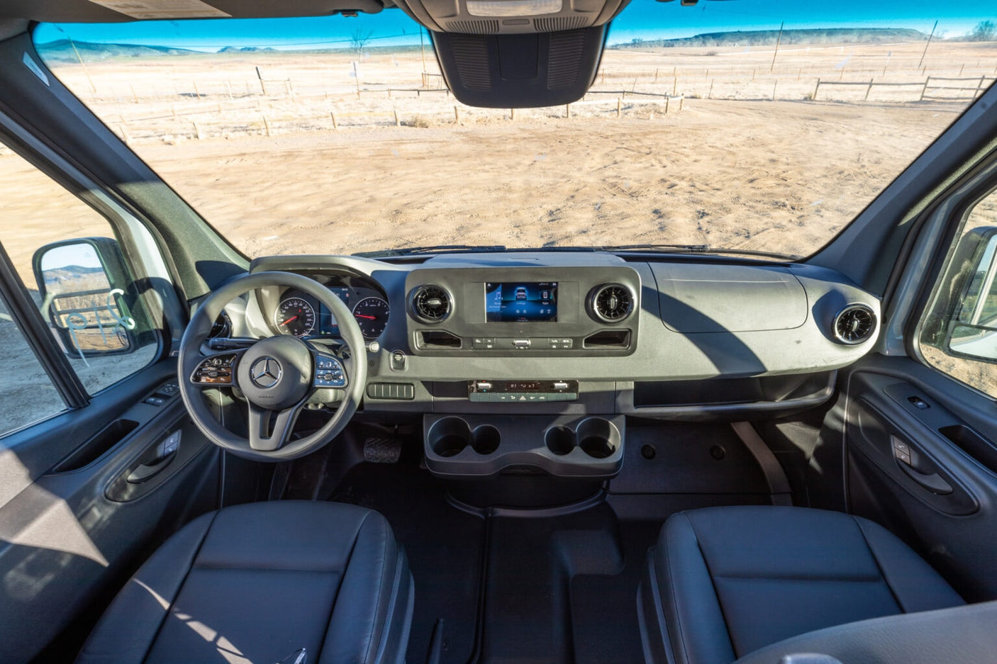 enjoying a sunny view of coastal homes and the ocean.|Experience van life: a grey rv rental camper van parked by a cliff on a coastal pullout