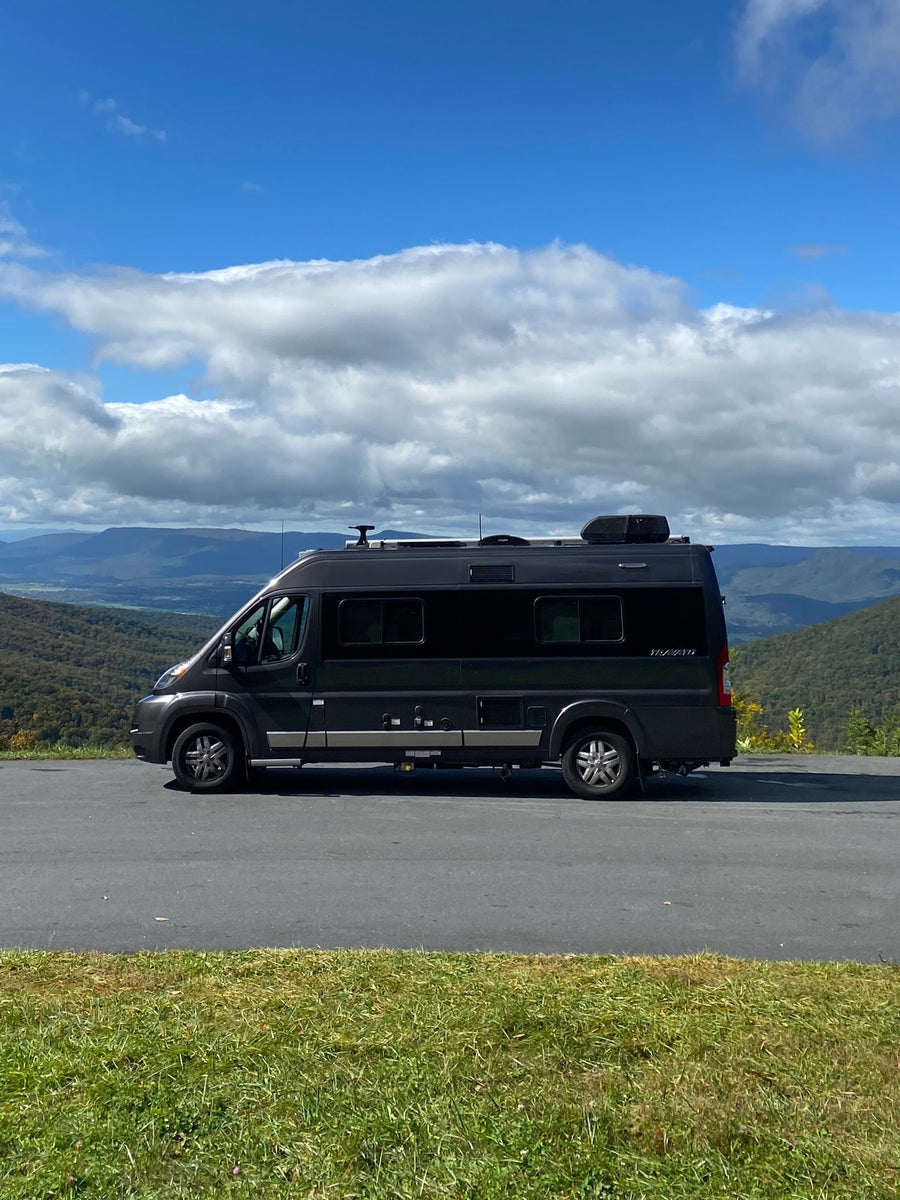 Black RV rental camper van parked on a paved mountain overlook