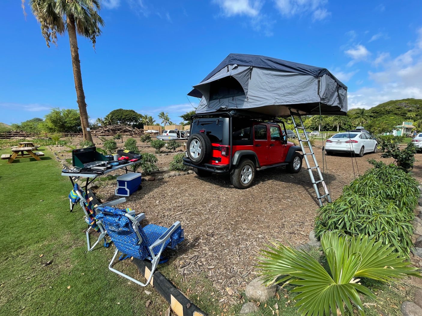 Red Jeep Wrangler RV rental with a rooftop tent and camping setup, ideal for outdoor adventures.
