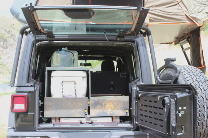 Open Jeep Wrangler with overland storage, cooler, water, and rooftop tent. Ideal for your next RV rental camping trip!