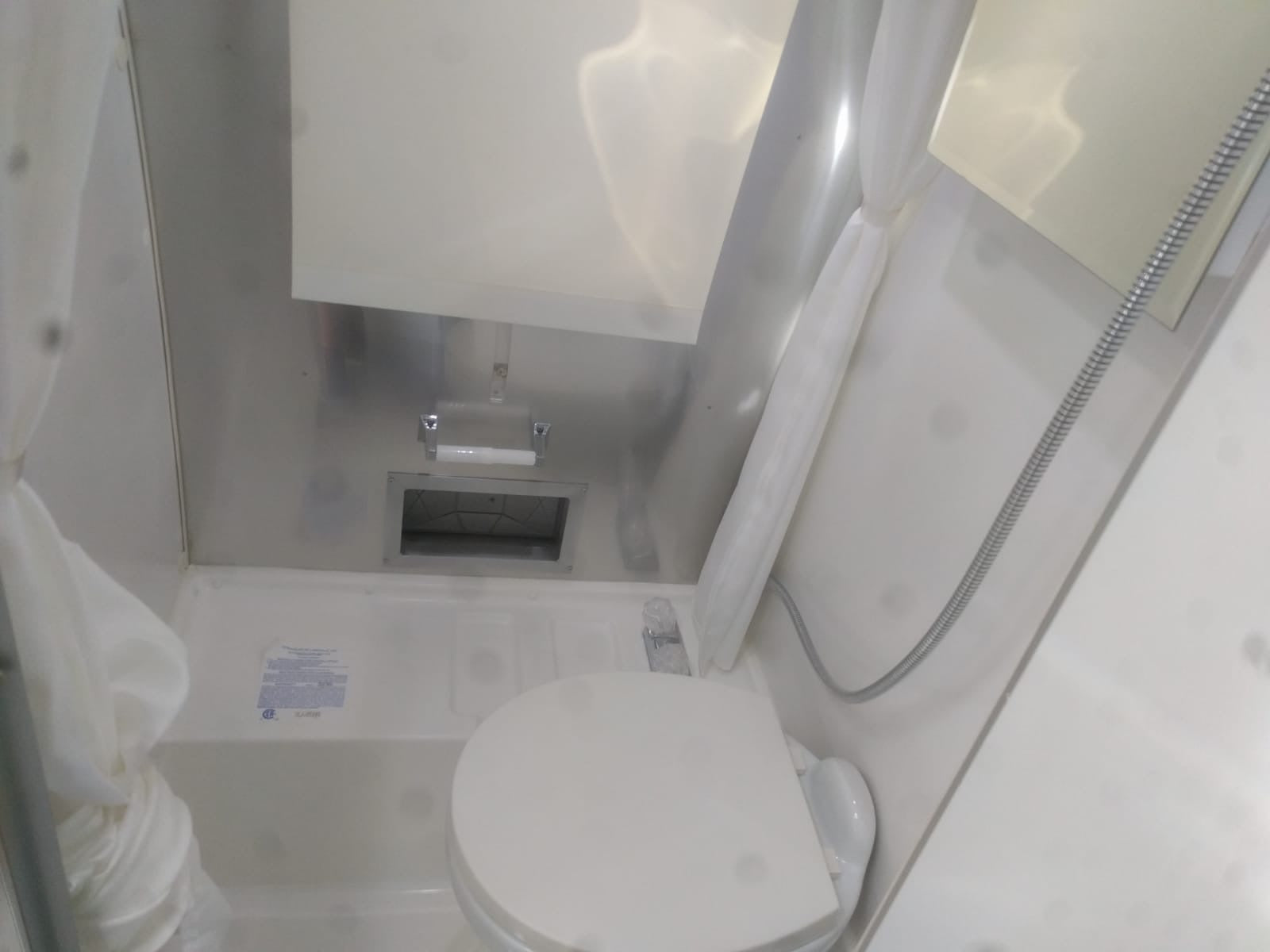 This RV rental features a compact wet bath with a toilet, shower, and toilet paper holder, maximizing space.