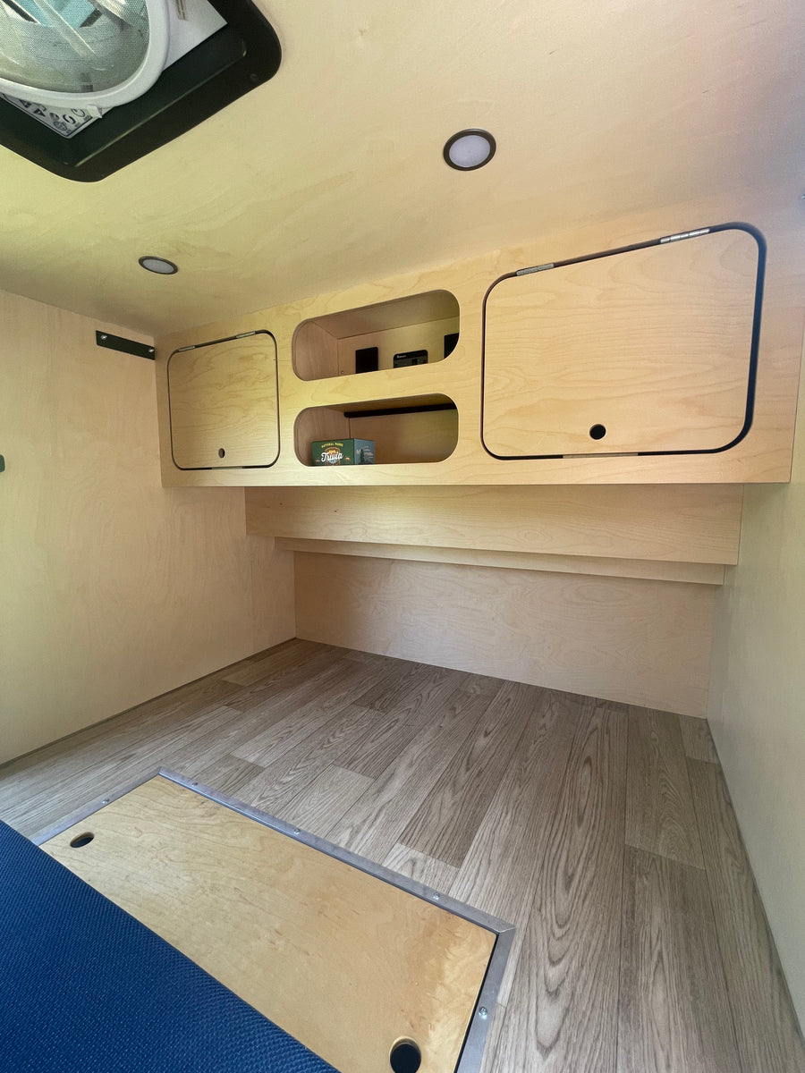 Clean and bright RV rental interior showcasing light wood paneling, built-in storage, and modern wood-look flooring.