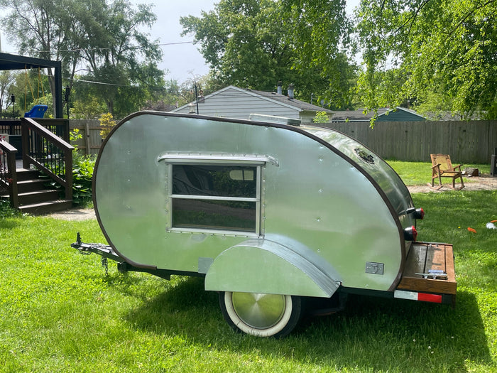 portable camping options.|Shiny aluminum teardrop camper on a lawn