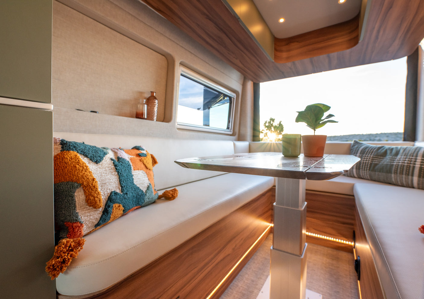 Bright and inviting RV rental dining nook with plush seating, adjustable table, and scenic window views.