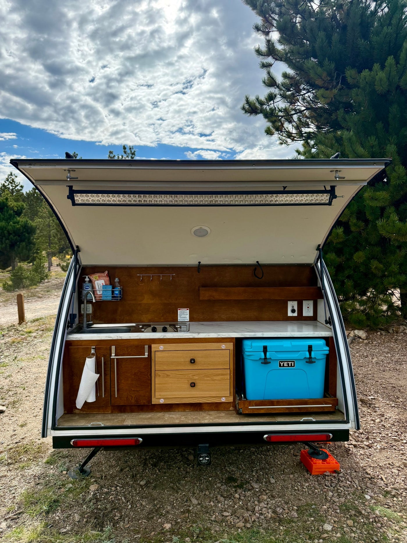RV rental teardrop camper galley, featuring a compact kitchen with sink, stove, cooler, and storage for outdoor cooking. — photo 3