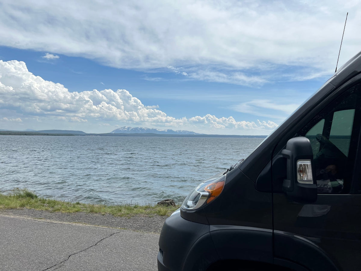 amidst towering light-colored chalk formations.|Scenic RV rental: Dark camper van parked roadside by a stream — photo 11