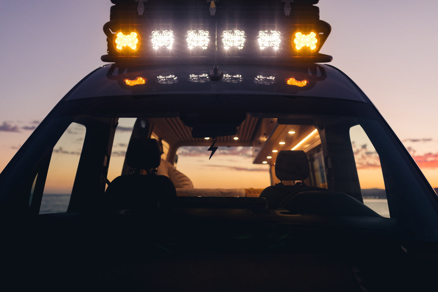 Experience a vibrant sunset from an **rv rental** van, showcasing its bright roof lights and comfortable interior.