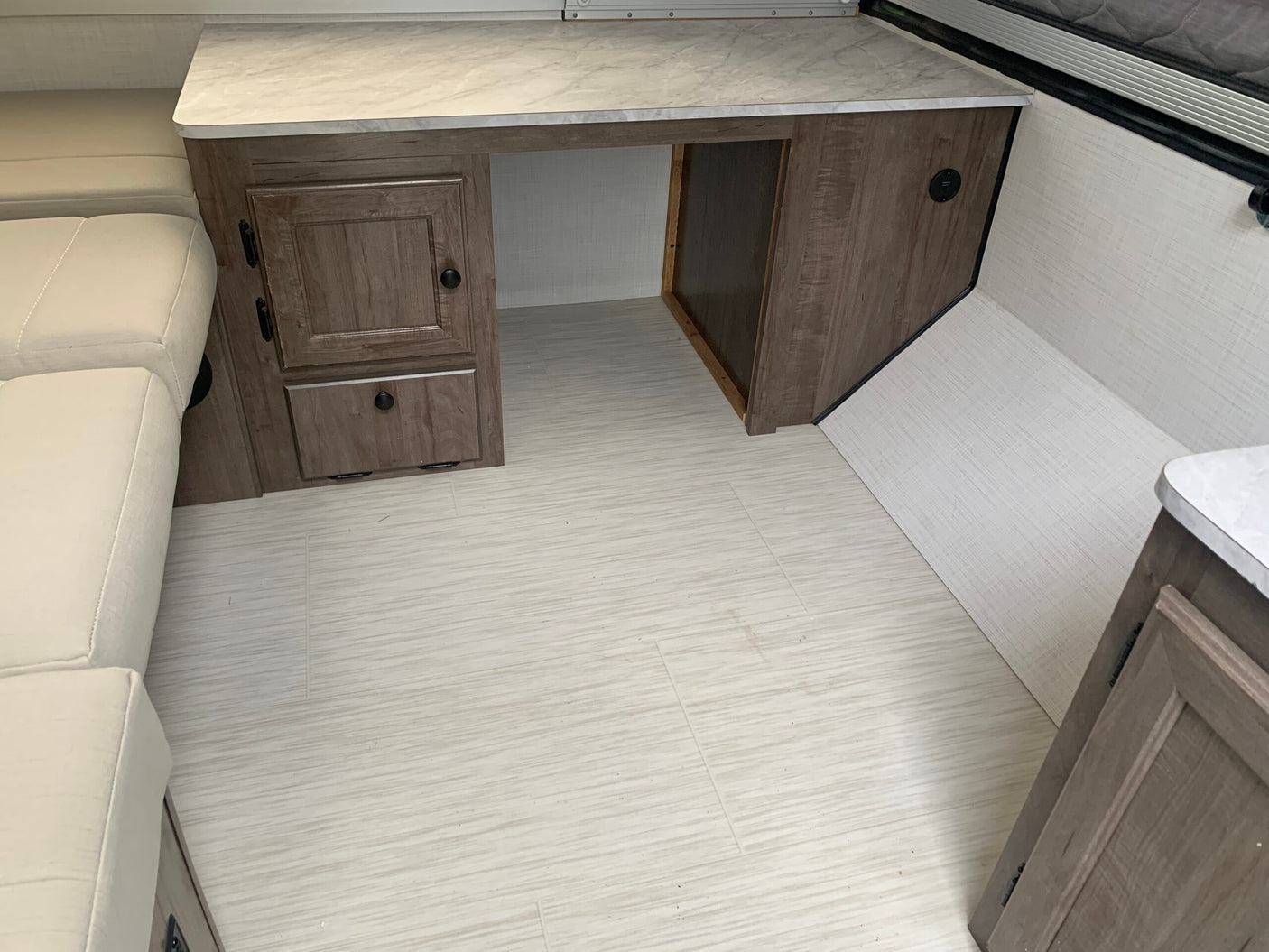 Clean rv rental interior featuring a desk with storage, light sofa, wood-look floor, and USB charging.