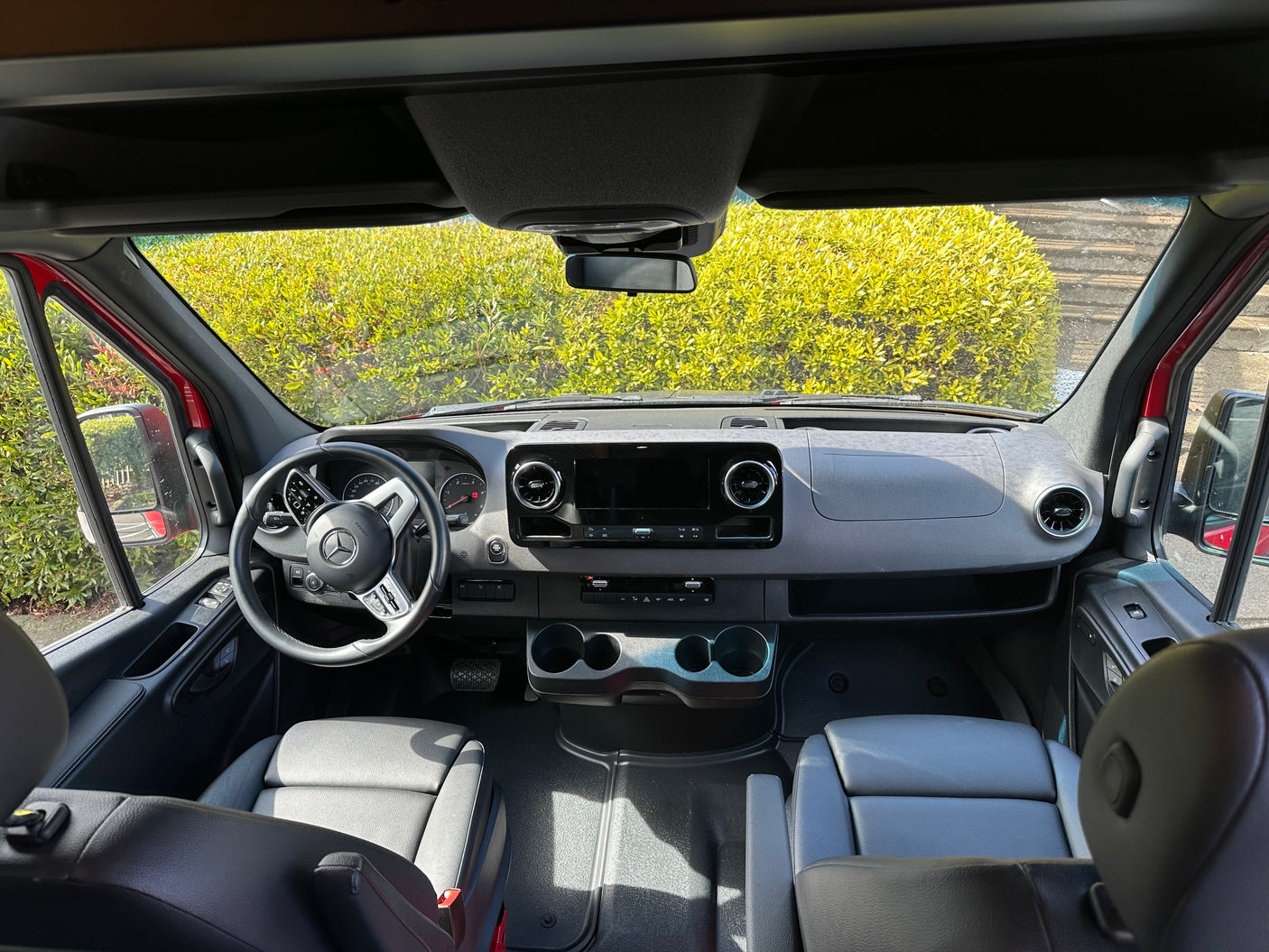 Spacious Mercedes Sprinter rv rental interior, showing dashboard, steering wheel, and front seats from a rear view.