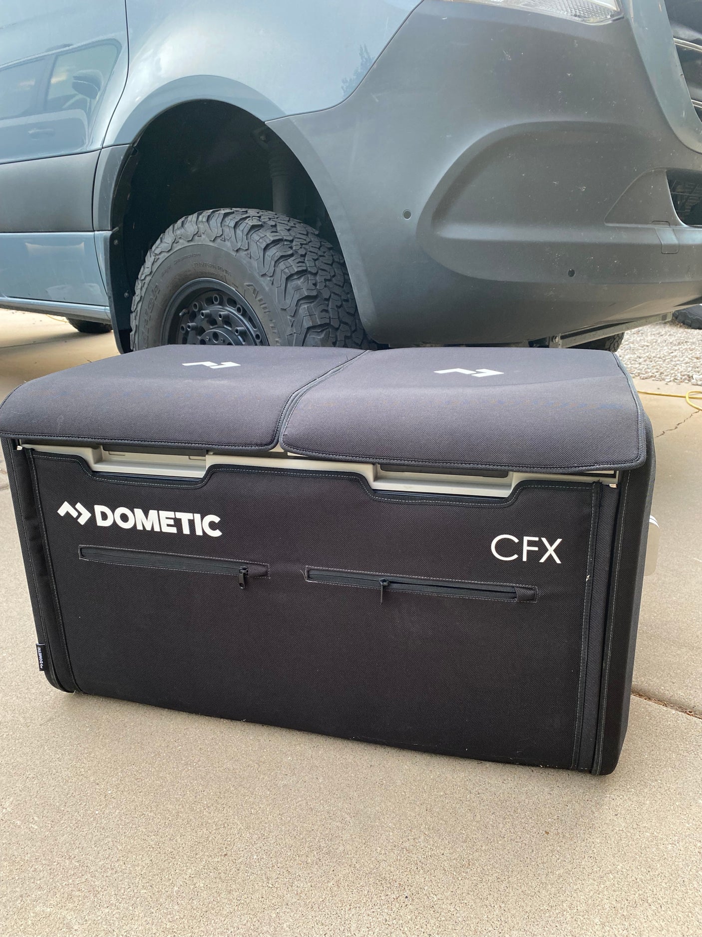 Black Dometic portable fridge (CFX) in front of an off-road RV rental van, ready for adventure.