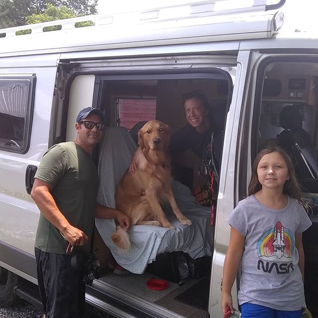 Happy family & Golden Retriever with their RV rental. Dad & daughter outside, mom & dog inside camper van. Great for pet travel!