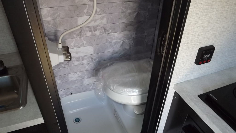 and refrigerator.|Inside an RV rental: a modern shower with faux grey tiles and an adjacent air conditioner.|RV rental AC unit: A Frigidaire air conditioner with an 11.0 EnerGuide rating