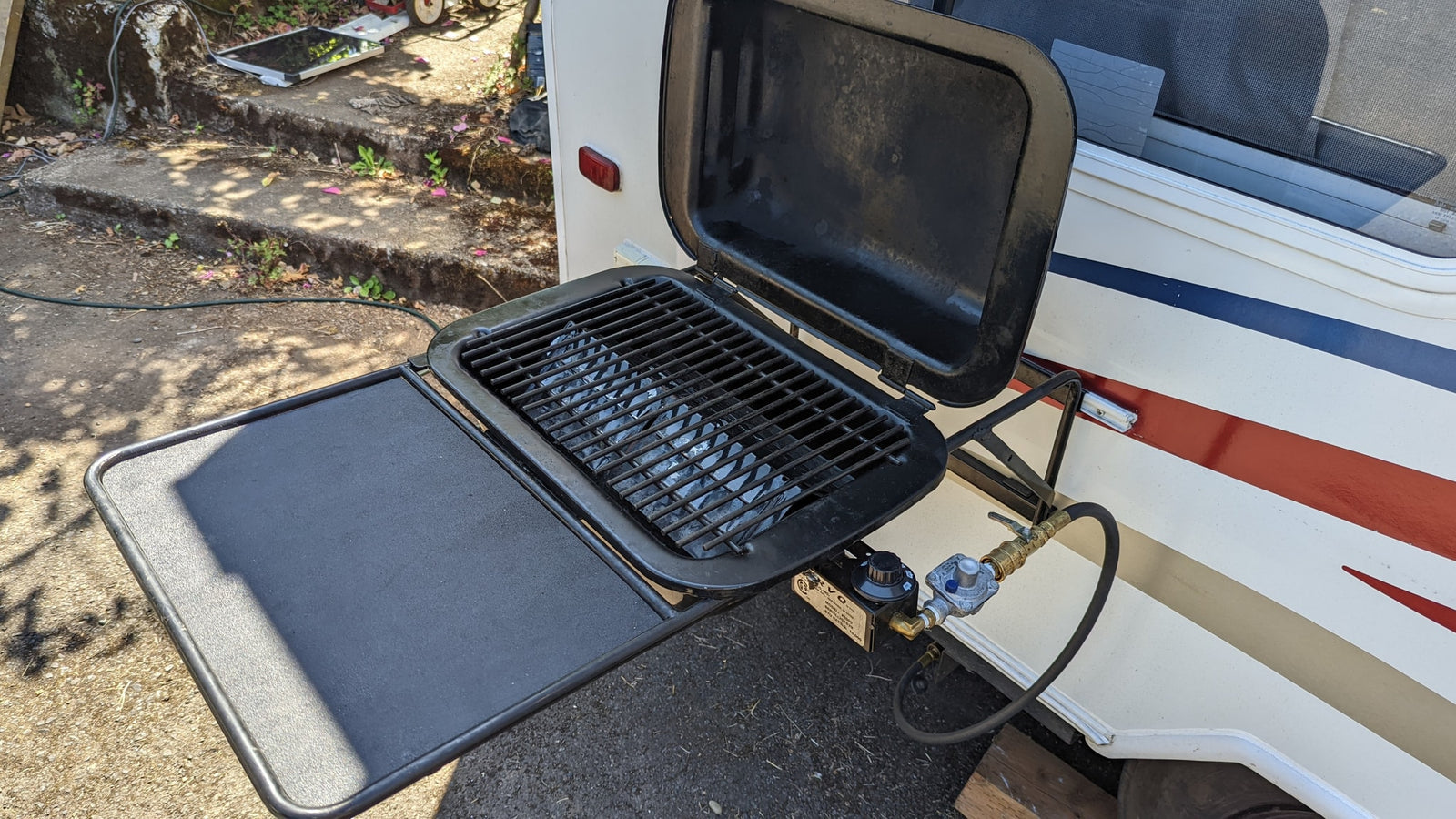 RV rental featuring a convenient side-mounted propane grill and attached table, ideal for outdoor cooking.