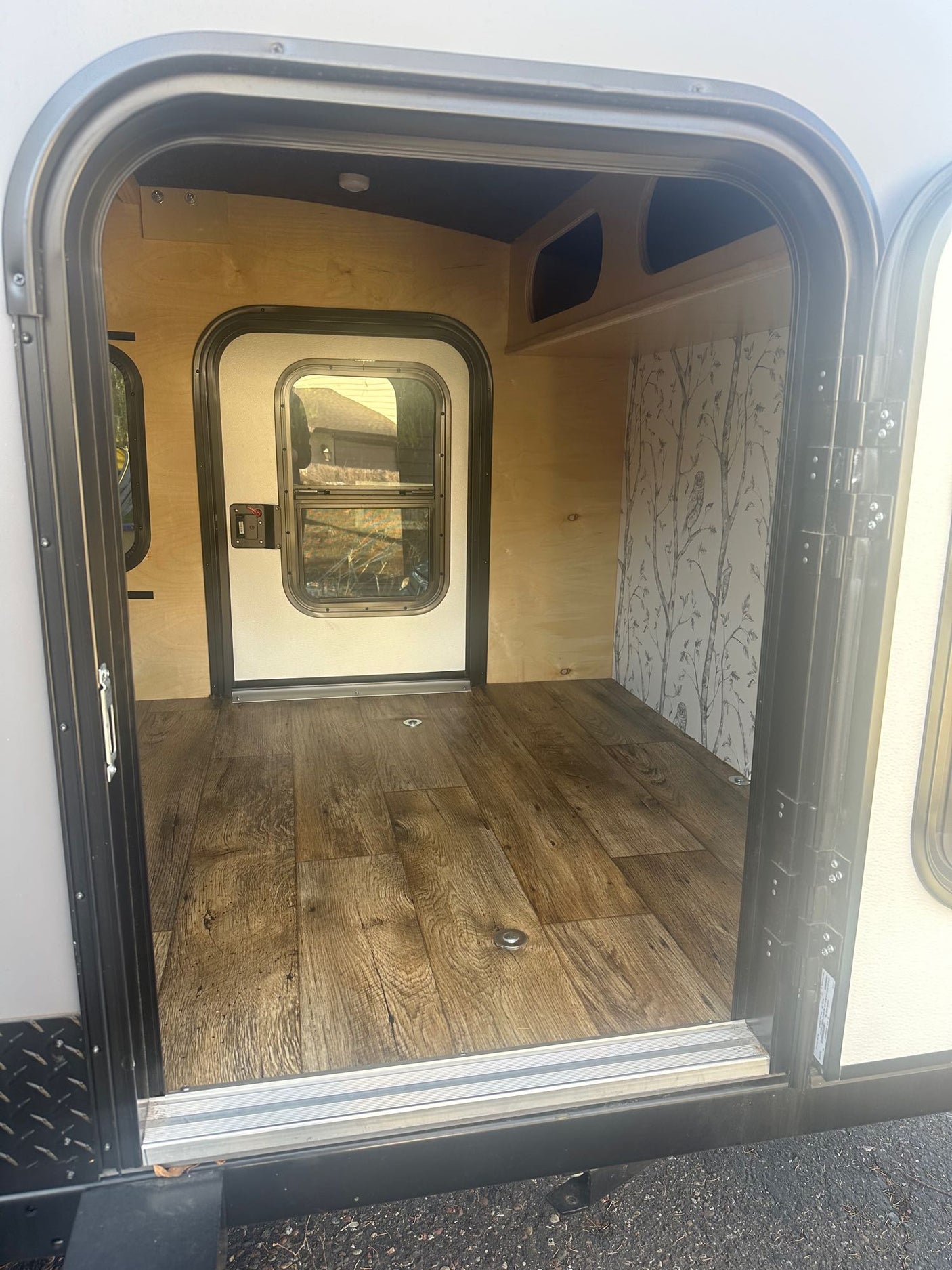 perfect for RV rental adventures. Features a mountain logo on the back window.|Open rear galley on a compact **RV rental** teardrop trailer