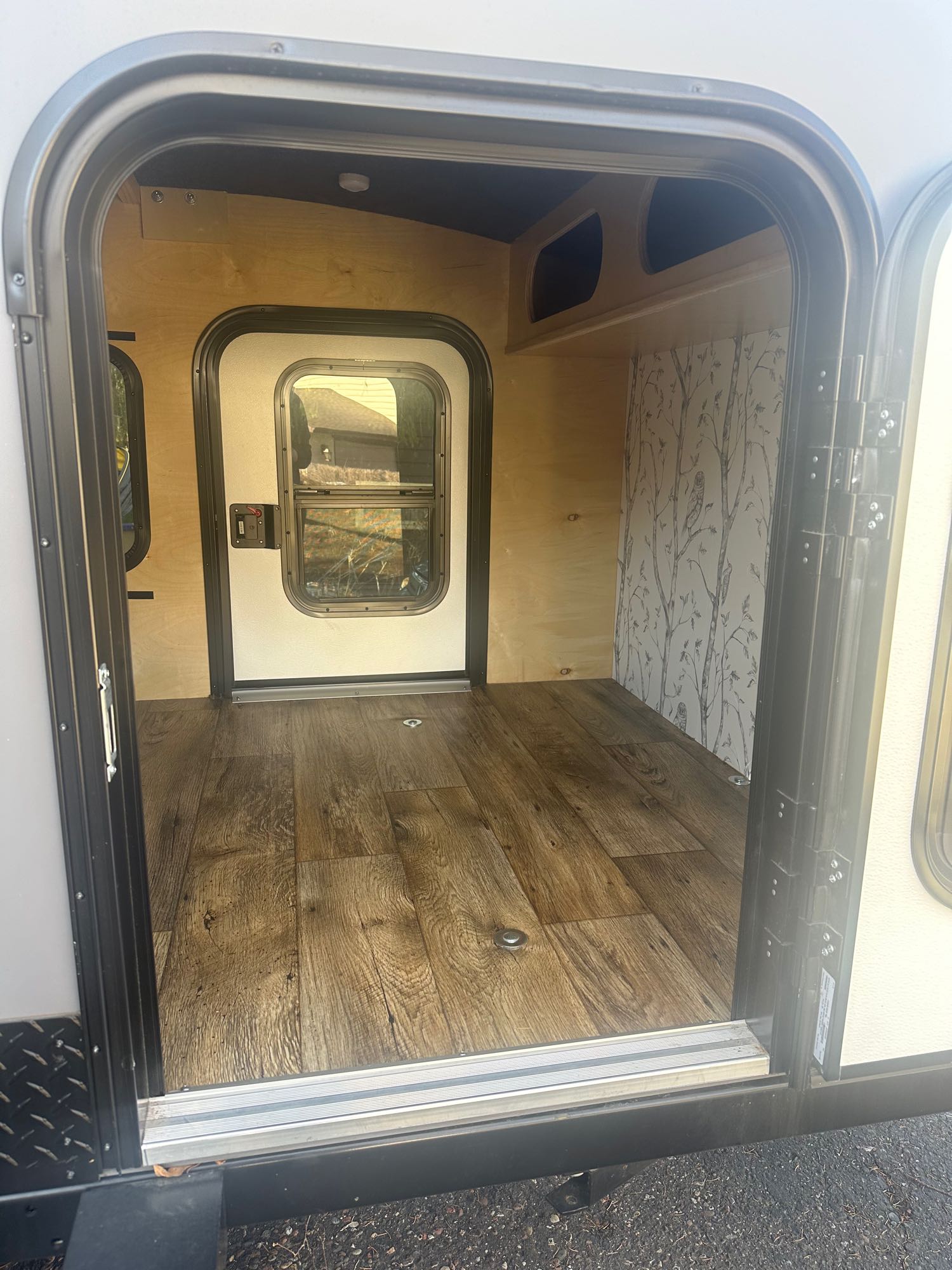 perfect for RV rental adventures. Features a mountain logo on the back window.|Open rear galley on a compact **RV rental** teardrop trailer